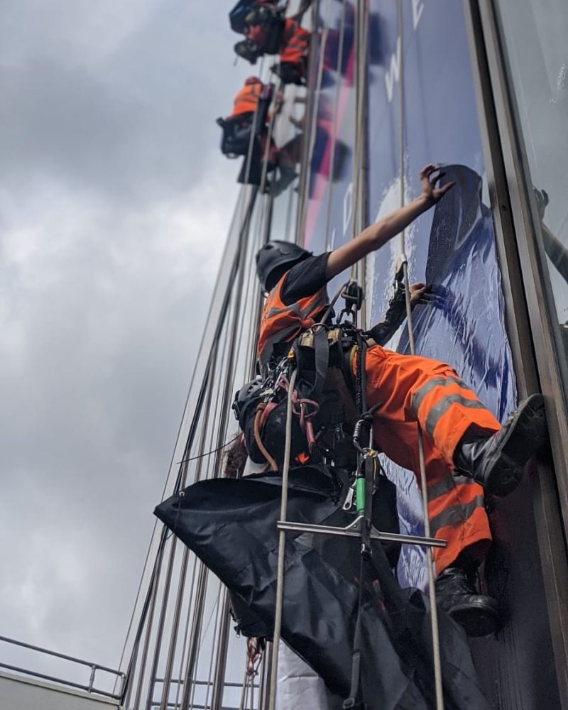 Abseilers using rope access to install high-visibility branding on buildings