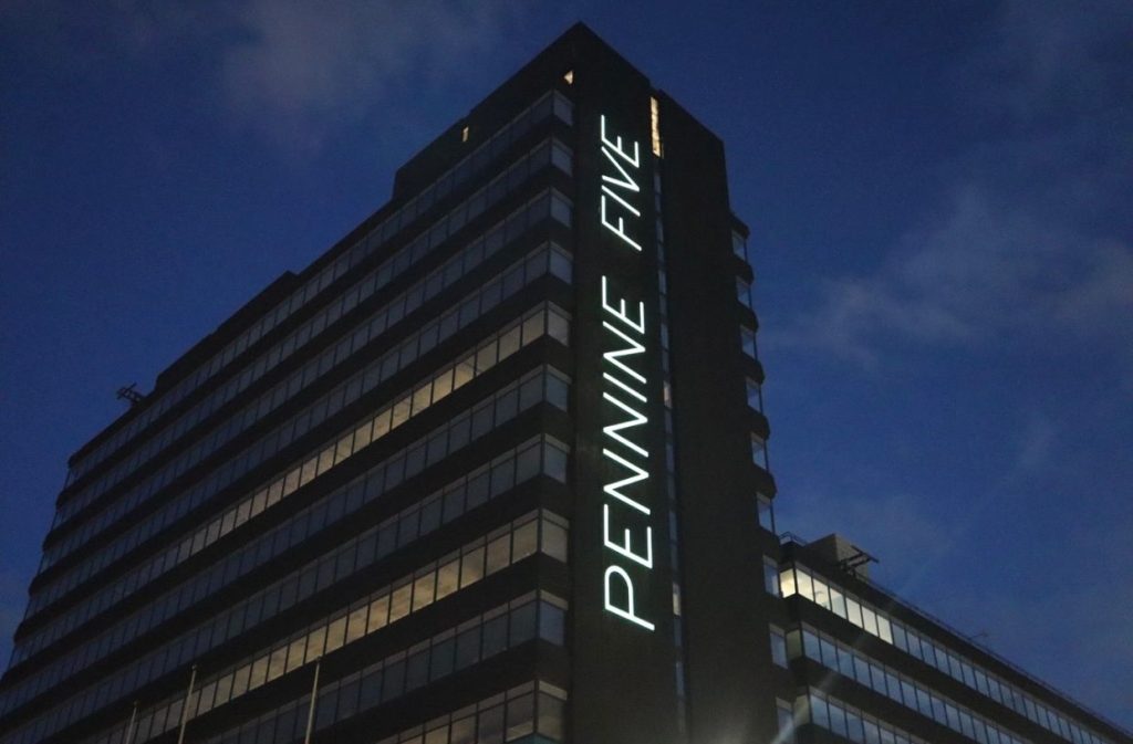 Illuminated signage installation with outdoor signage lighting on commercial building