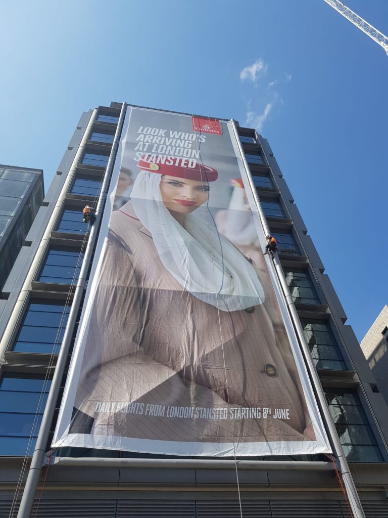 High-impact advertising banner installation via rope access. As part of out-of-home (OOH) marketing campaign.