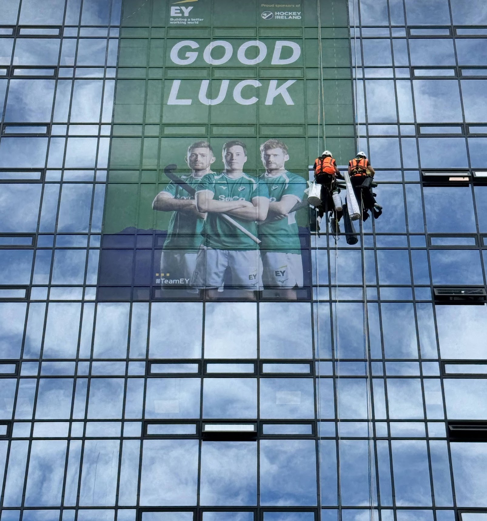 Abseilers using rope access to install vinyl graphics on glass building façade for sport event